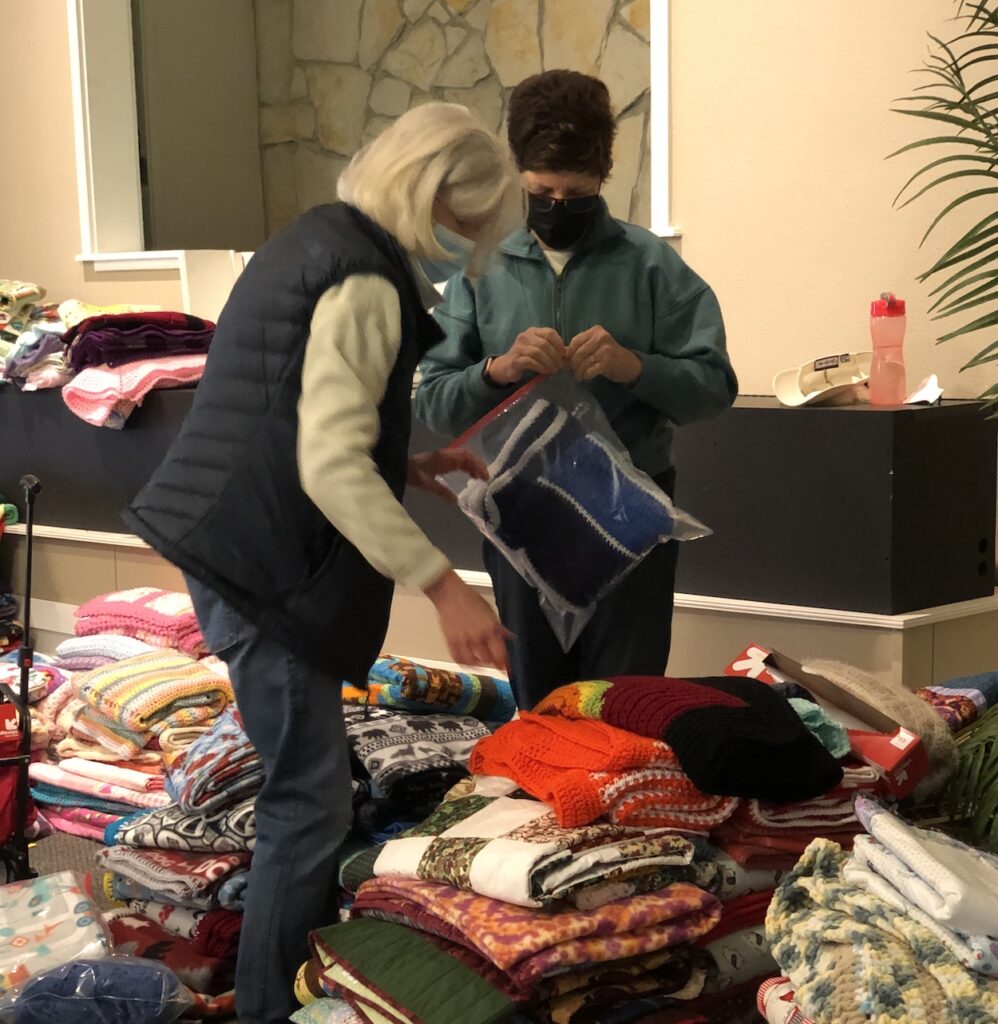Two STEAC volunteers sorting blankets for Holiday program