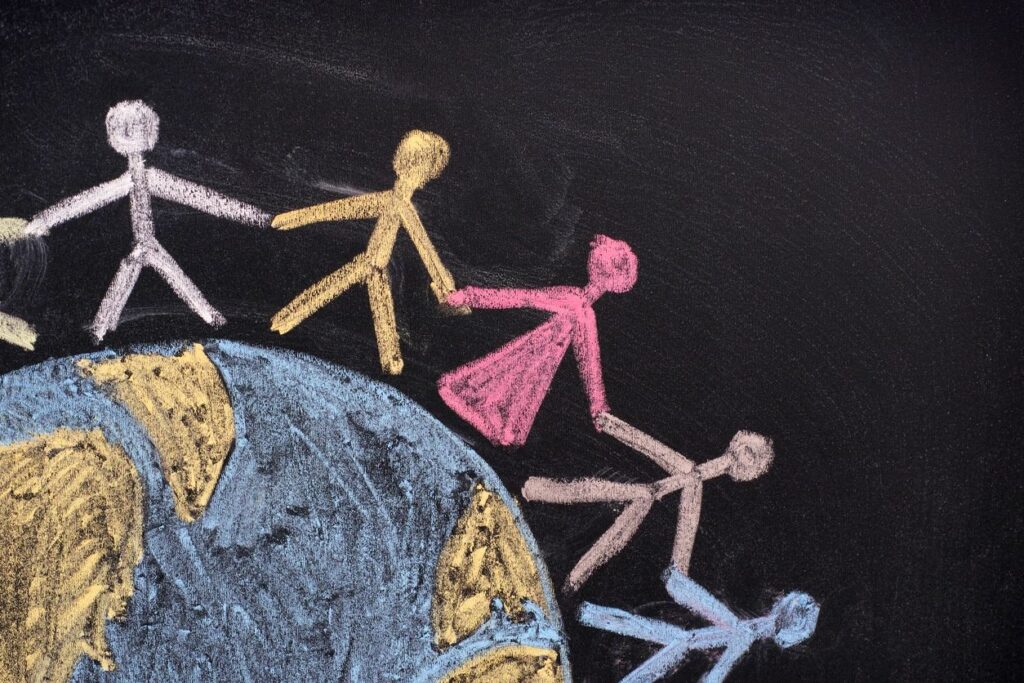 Chalk drawing of a world and outlines of people holding hands